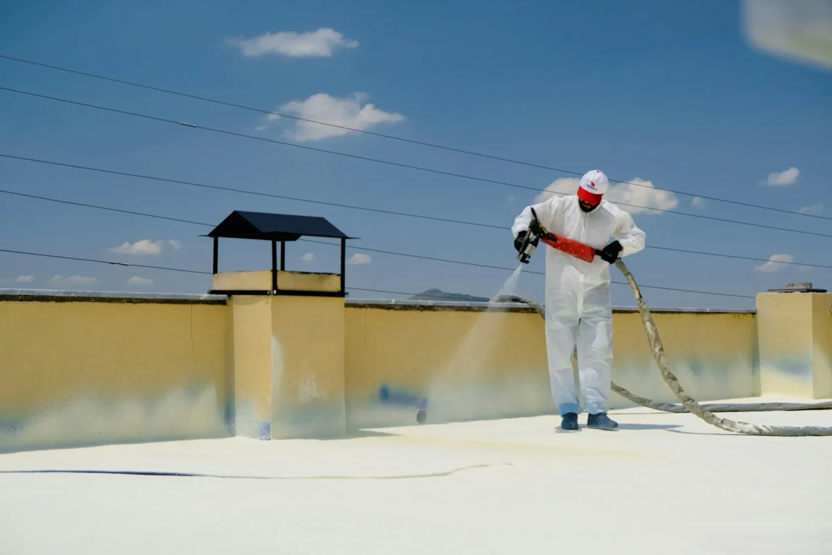 Worker applying a protective coating on a commercial flat roof